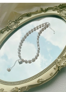 Dettaglio collana doppia di perle barocche con pendente a cuore su specchio vintage