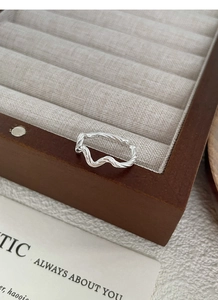 Detail of S925 sterling silver ring featuring a polished wavy twisted open design