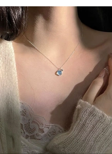 Detailed view of S925 sterling silver necklace with sea blue stone on model's neck