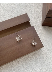 Macro detail of S925 sterling silver geometric pearl stud earrings on a wooden display