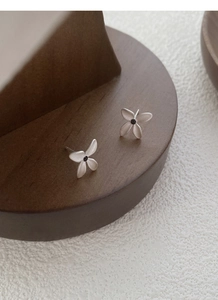 Macro shot of silver gardenia flower stud earrings with a matte finish and black center