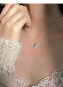 Close-up of S925 sterling silver necklace with a round sea blue gemstone on a woman neck