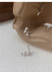 Detail of silver pearl and rhinestone curved earrings on creative paper background