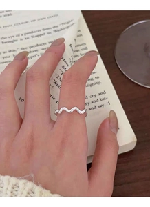 Close-up of S925 sterling silver wavy twisted ring worn on finger with artistic backdrop