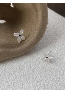 Macro detail of matte S925 silver gardenia flower stud earrings on textured artistic background
