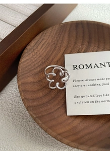 Detail view of S925 sterling silver hollow flower ring on a minimalist wooden tray