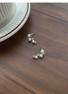 Macro shot of S925 sterling silver pearl earrings with sparkling crystals in an arc