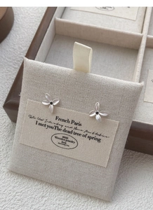 Macro detail of silver gardenia stud earrings with matte finish and black center stone