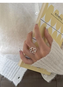 Silver hollow flower ring worn by a model in a warm, minimalist lifestyle setting