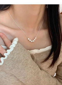 Détail du collier avec nœud en argent S925 et perles porté sur le cou d'un modèle