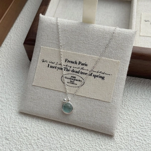S925 silver necklace with round sea blue gemstone pendant on a wooden jewelry display