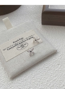 Detail of matte S925 silver gardenia earrings with black center on fabric bag