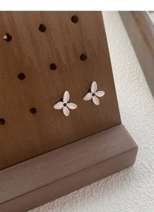 Detailed macro view of S925 sterling silver gardenia earrings with matte texture and black studs