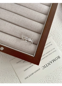 Macro view of silver bow-shaped rings on a gray velvet tray with decorative card