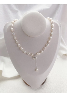 Dettaglio della collana di perle barocche con cuore su espositore metallico argento