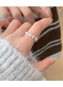 Detail of silver S925 bow-shaped stacking ring worn on finger with soft knitwear
