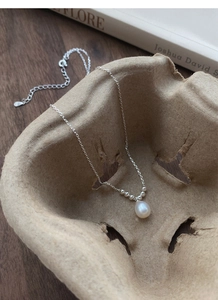 Detail of S925 sterling silver hook with freshwater pearl pendant on a textured tray