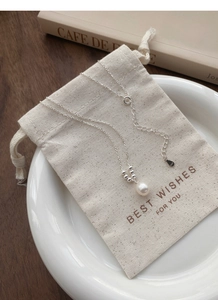Detail of S925 silver necklace with a freshwater pearl pendant on a soft linen bag