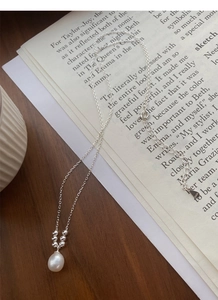 Detail of S925 silver necklace with a freshwater pearl pendant on a subtle cross chain