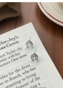Macro shot of silver bow tie stud earrings on minimalist aesthetic background paper