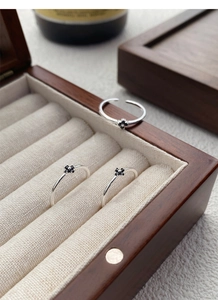 Détail de bagues en argent S925 avec motif floral en zircon noir sur une boîte à bijoux en bois