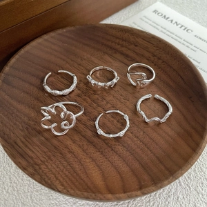 Set of 6 minimalist S925 silver rings with heart, bow and wave designs on wood