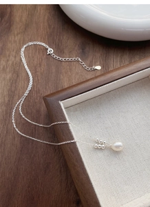 Close-up of S925 silver necklace featuring a white freshwater pearl on a silk cloth
