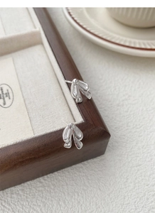 Macro shot of 3D silver bow-knot earrings featuring a high-polish metallic finish