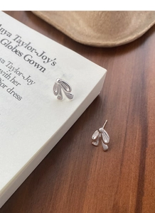 Macro shot of polished S925 sterling silver bow tie earrings on minimalist book pages