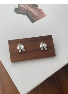 Macro detail of silver S925 bow-tie stud earrings on dark wood texture background
