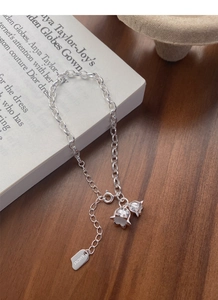 Close-up of S925 silver lily of the valley bracelet with a lucky tag on a vintage book