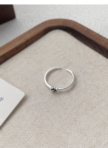 Détail d'une bague en argent S925 avec trèfle noir sur un tissu de lin texturé