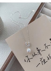 Detail of S925 sterling silver necklace with freshwater pearl pendant on a beige display card