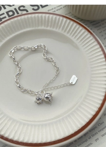 Detail of S925 silver lily bracelet with flower charms and a lucky rectangular tag