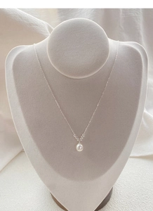Detail of S925 silver necklace with elegant freshwater pearl pendant on a grey display stand