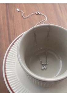 Détail d'un collier en argent S925 avec zircon de cœur et perle sur une tasse
