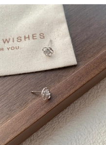 Détail des boucles d'oreilles roses en argent ajourées avec zircon sur plateau bois