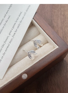 Detail of S925 sterling silver bow tie earrings on a walnut wood jewelry box