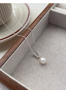 Close-up of S925 silver necklace with white freshwater pearl pendant on a linen tray