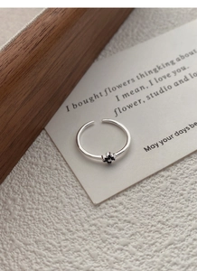 Détail de bague ajustable en argent S925 avec fleur noire sur une carte vintage