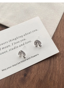 Macro detail of silver bow tie stud earrings on a vintage paper art card background