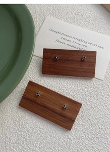 Detail view of two pairs of S999 silver black clover flower stud earrings on wood