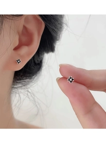 Close-up of S999 sterling silver black four-leaf clover stud earrings on ear