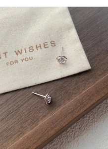 Macro des boucles d'oreilles roses en argent avec pétales ajourés et zircon brillant au centre