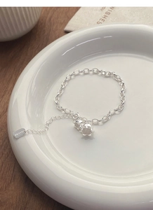 Detail view of S925 silver lily of the valley bracelet with lucky tag on ceramic plate