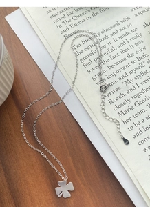 Detailaufnahme der Kleeblatt-Halskette aus S925 Sterlingsilber auf Holz und Zeitungsunterlage