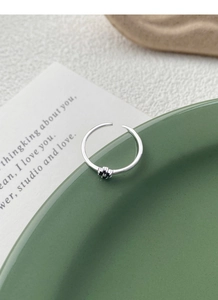 Gros plan détaillé d'une bague en argent S925 avec breloque fleur noire sur fond vert
