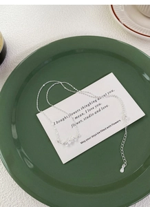 Gros plan sur un collier en argent avec pendentif papillon et feuille de ginkgo élégant