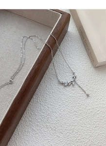 Macro detail of S999 silver wheat ear necklace with zircon inlay on a wooden tray