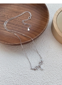 Macro detail of S925 silver wheat necklace with shimmering zircon drop on wooden stand